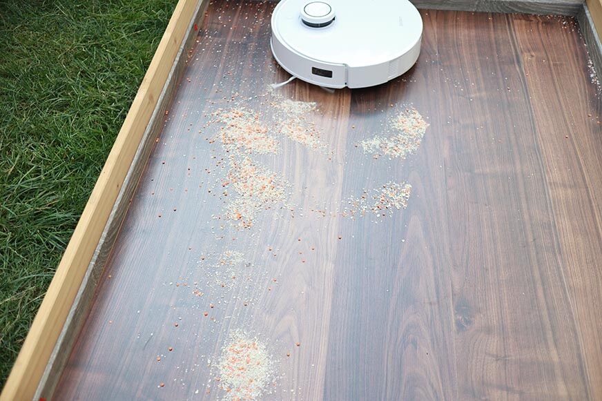 ECOVACS DEEBOT T10 reinigt Haferflocken auf einem Laminatboden im Saugtest.